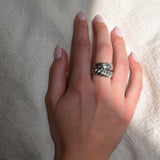 Hand wearing a silver ring on a textured white background